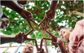 People standing in circle joining hands to form star in the center with their fingers